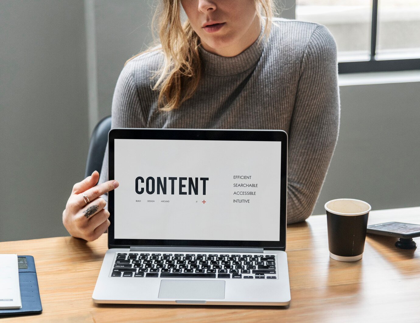 A girl pointing towards the word "content" on a laptop screen.