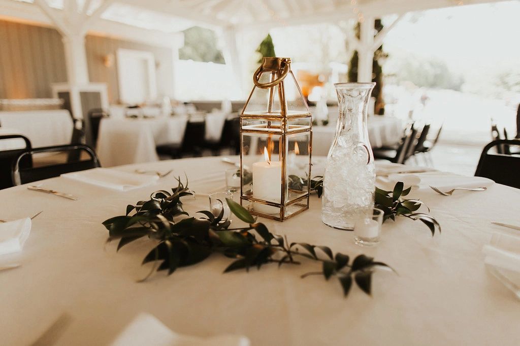 Table centerpiece with leaves and lantern and vase