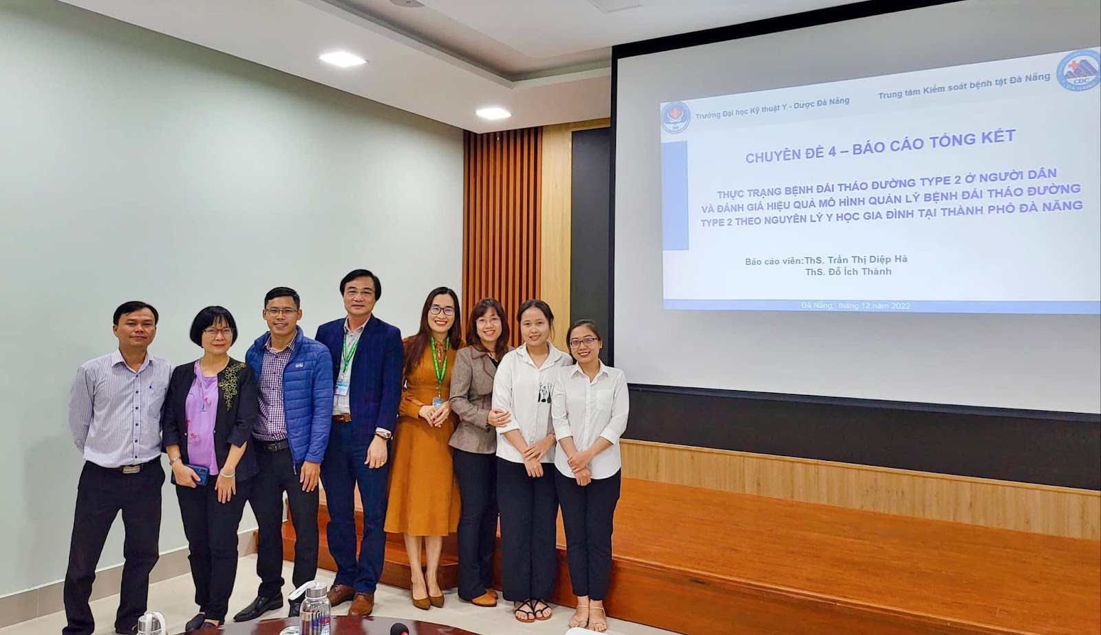 A group of people standing in front of a projector screenDescription automatically generated