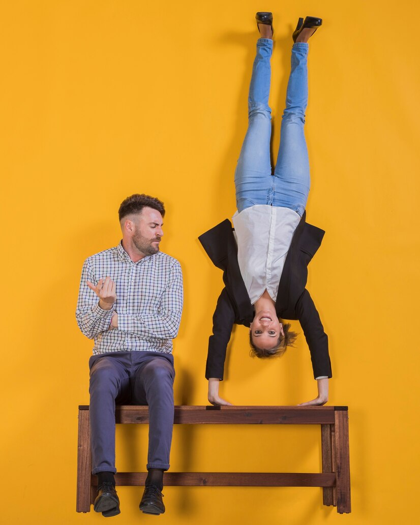 A man sitting and a woman doing a handstand on a bench.