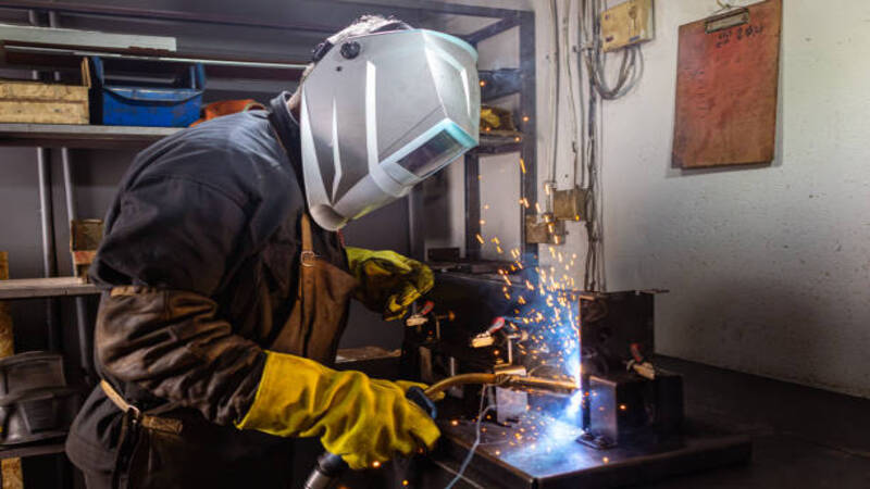 A welder is welding metal pieces. 
