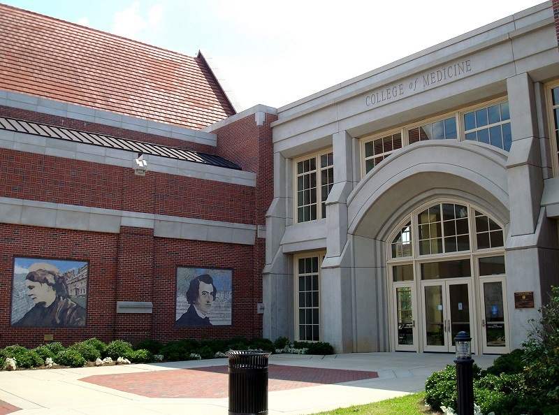 A photo of the front entrance of the Florida State University College of Medicine building with greenery surrounding it.