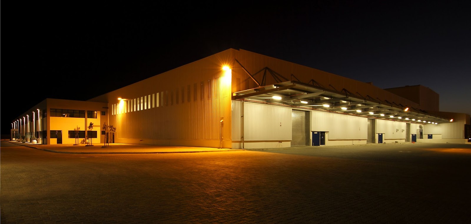 Illuminated warehouse exterior at night for security.