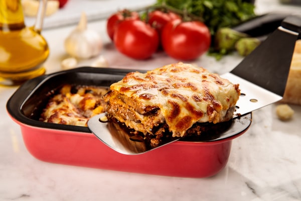 A slice of eggplant lasagna being lifted from the baking dish in an enticing presentation
