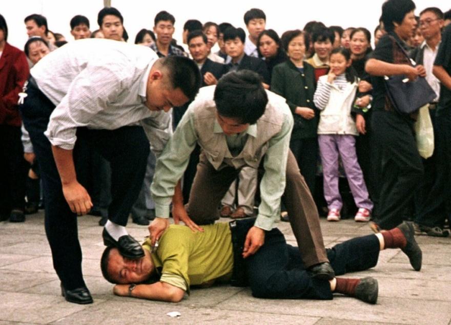 Hai cảnh sát mặc thường phục bắt giữ một học viên Pháp Luân Công tại Quảng trường Thiên An Môn ở Bắc Kinh, vào ngày 31/12/2000. (Ảnh: AP Photo/Chien-min Chung)