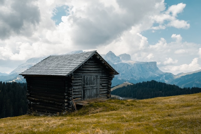 A grey wooden house with a sloping roof on the edge of a cliff