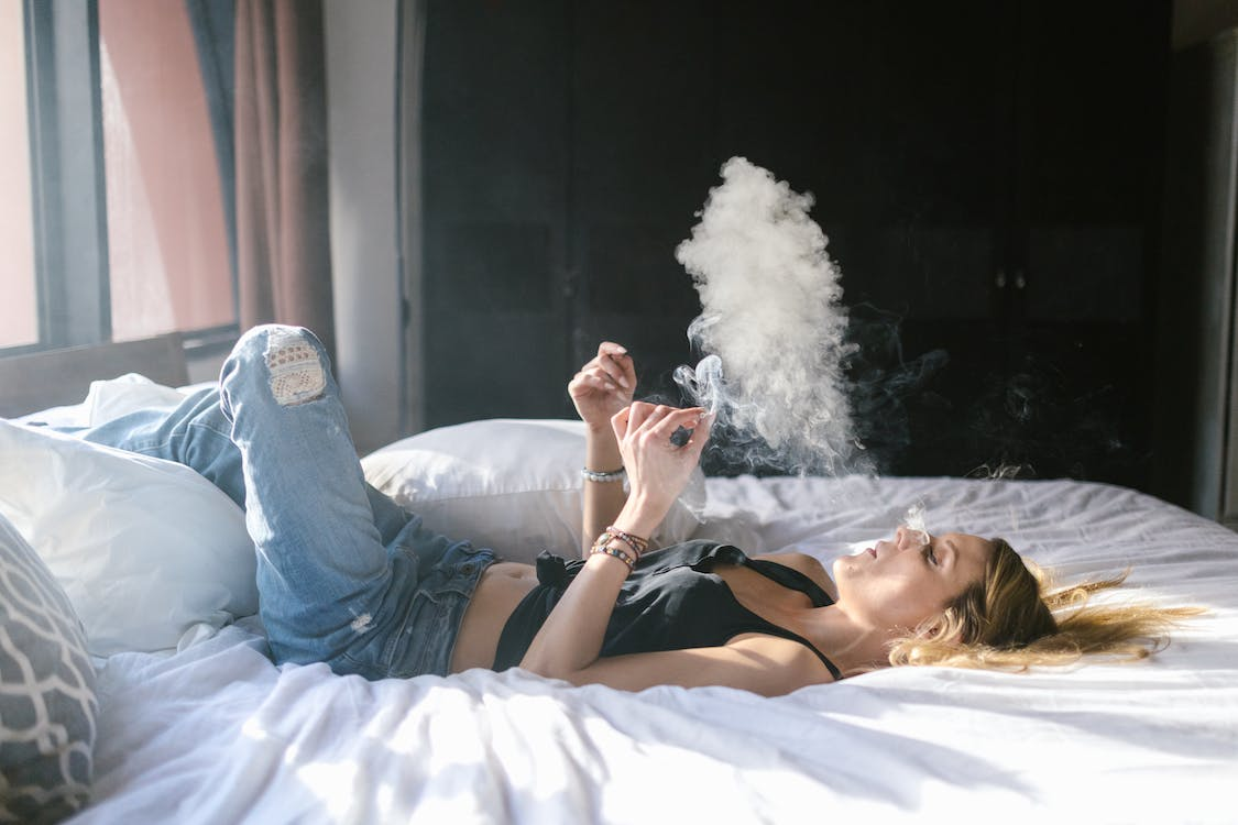 a woman sitting in bed enjoying a smoke