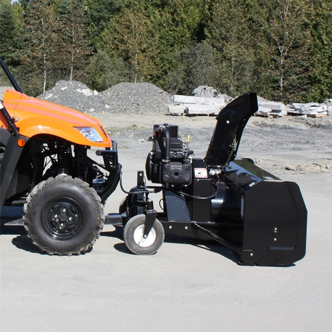 A side-view image of a Kubota RTV Snowblower by Bercomac, installed and parked on a concrete lot.