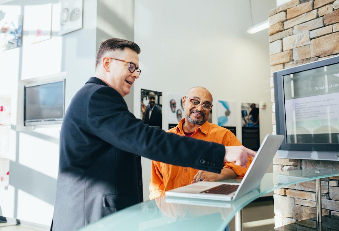 Two business professionals discussing capacity utilization and pointing at a laptop computer