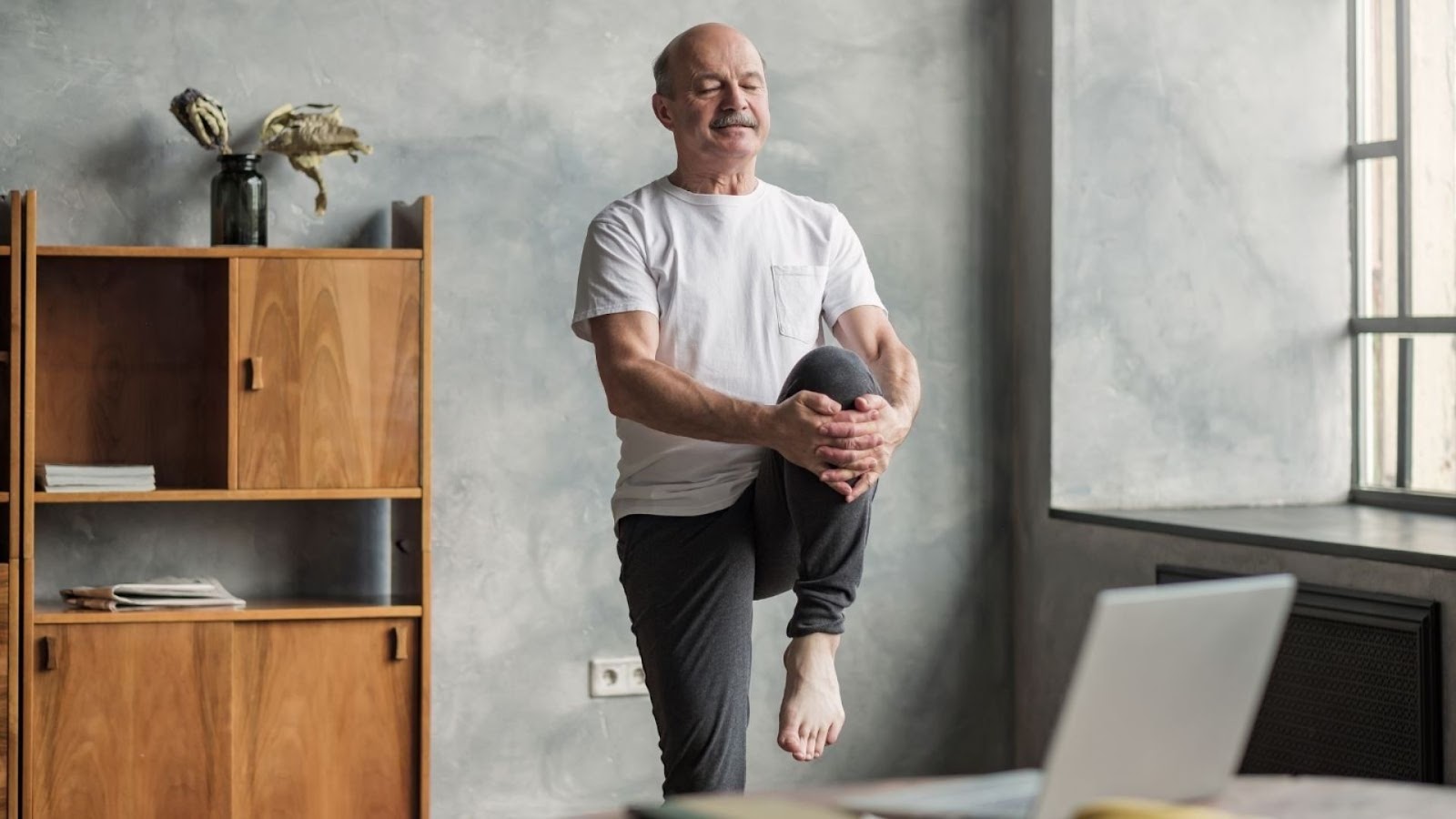 Hombre de mediana edad haciendo ejercicios de equilibrio en casa.