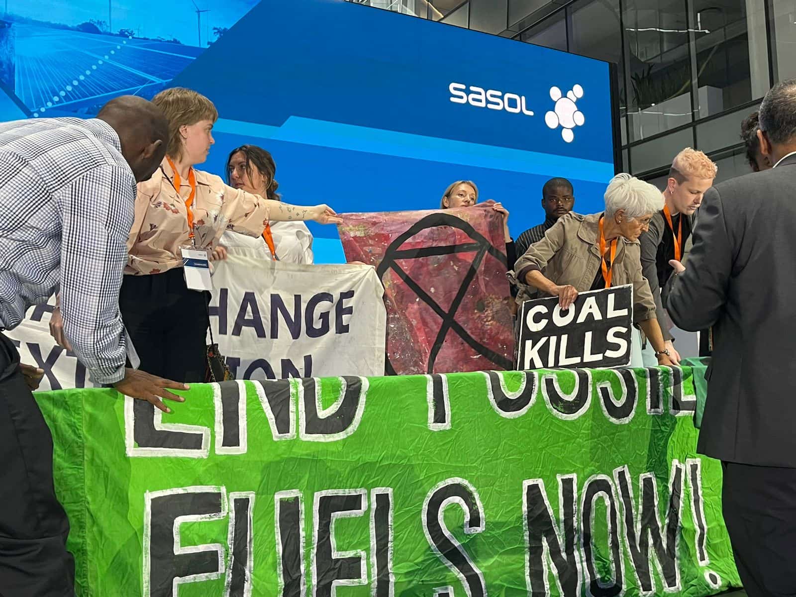Rebels storm the stage and stand with banners at the Sasol AGM