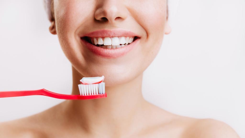 femme avec un visage souriant et une brosse à dents
