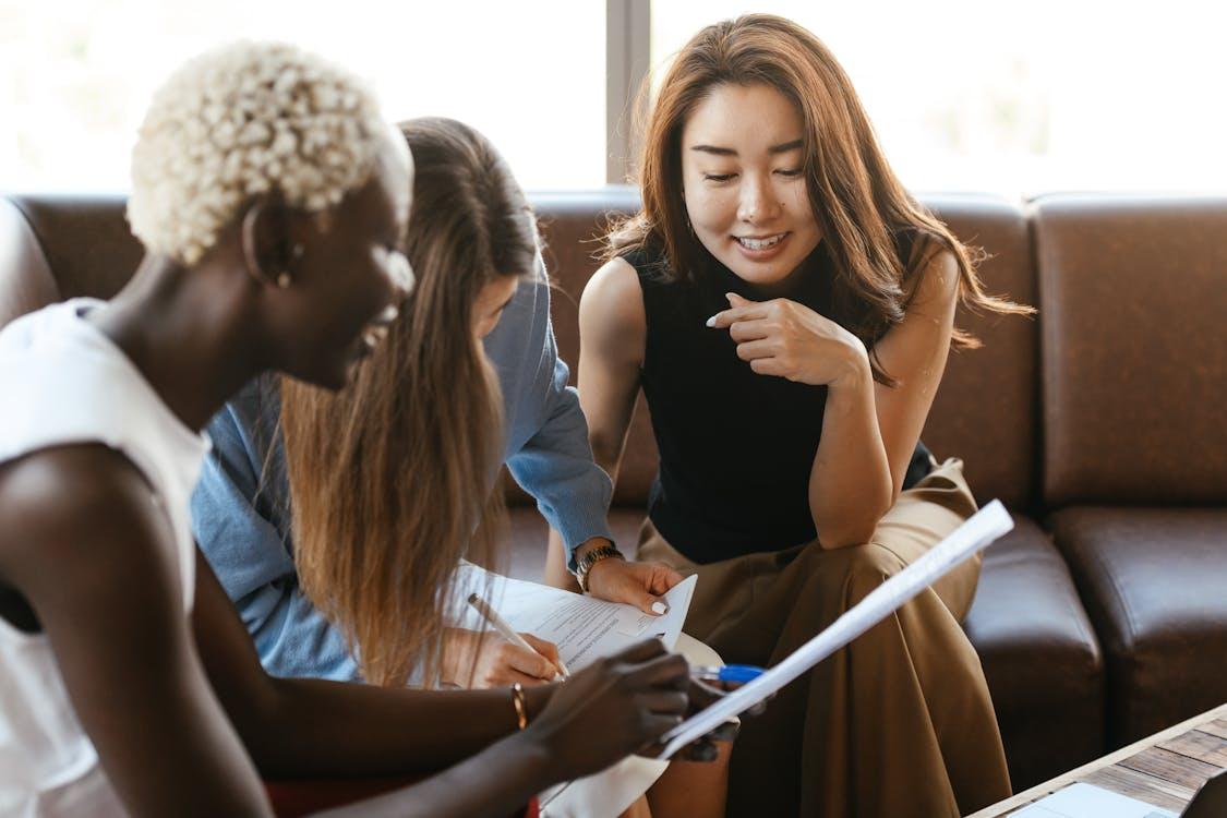 Free Multiethnic cheerful colleagues talking about job and working with documents Stock Photo