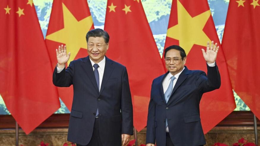 Vietnam's Prime Minister Pham Minh Chinh, right, and the China's President Xi Jinping wave to media members as they pose for a photo during a meeting at the government office in Hanoi, Vietnam, Wednes