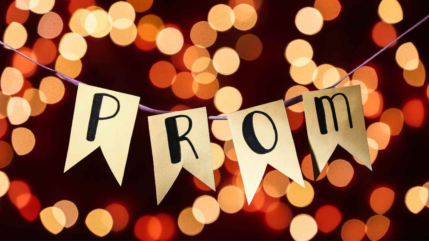 Prom Captions For Instagram - A banner spelling out "PROM" with individual letters on triangular flags, strung up on a line, with a backdrop of warm, out-of-focus lights.