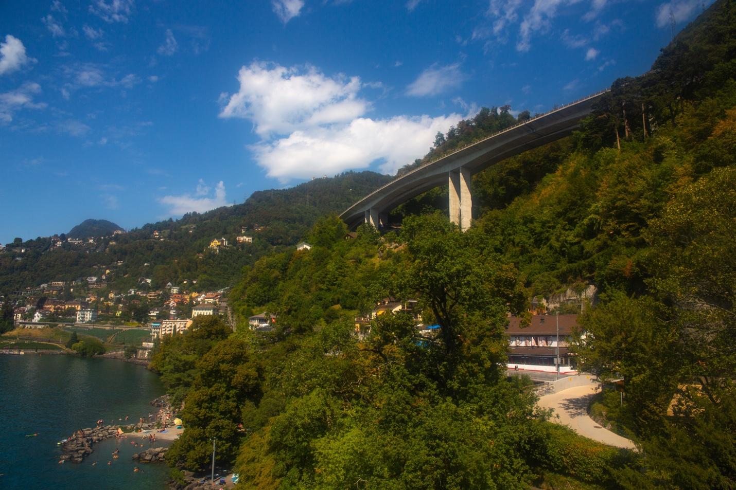 A bridge over a hill with trees and water

Description automatically generated