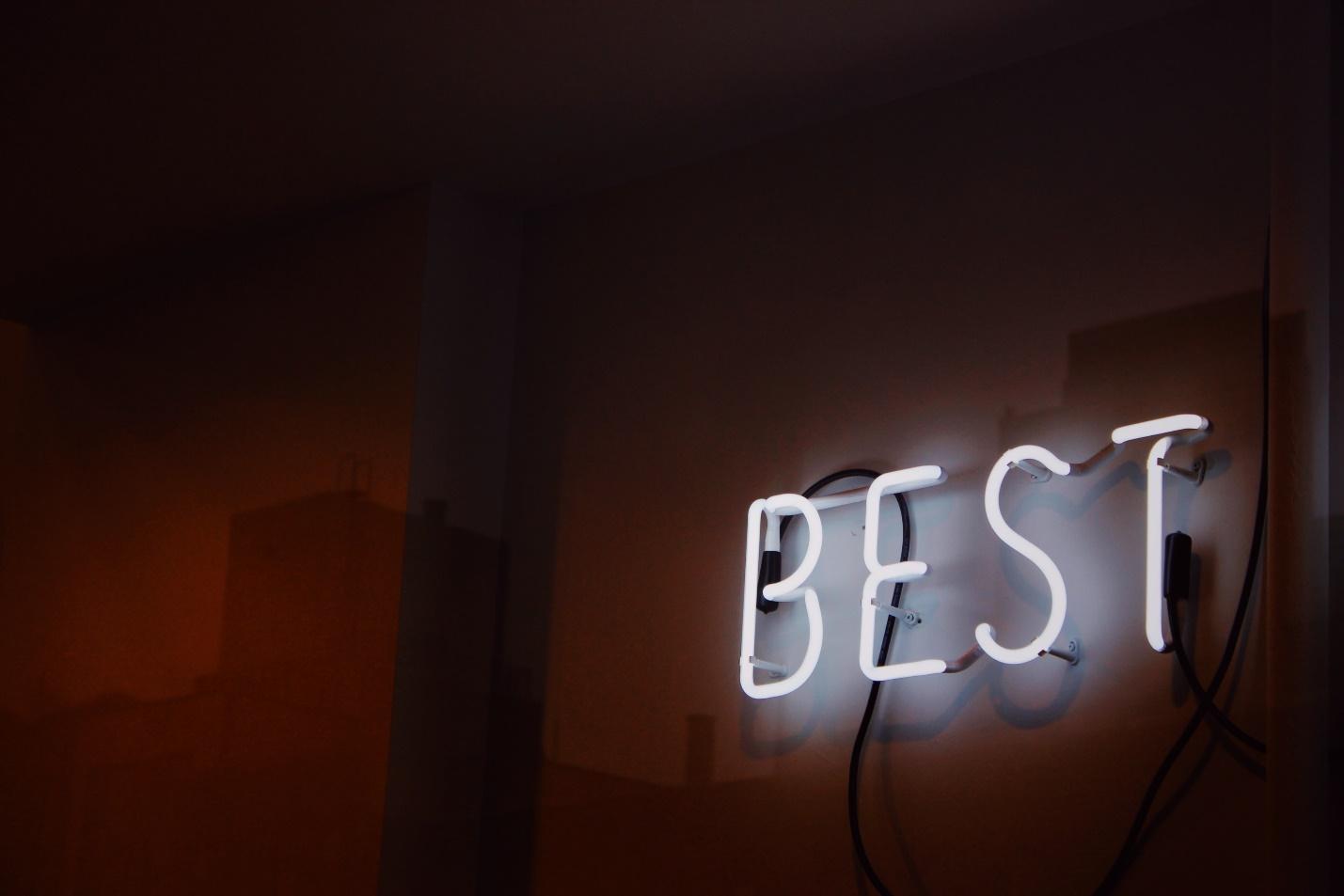 A neon sign on a wall that says "best"