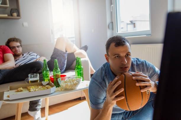 Young adult males watching basketball game and drinking beer at home Young adult males watching basketball game and drinking beer at home Why Live Streaming NBA Games Is A Game-Changer For Fans stock pictures, royalty-free photos & images