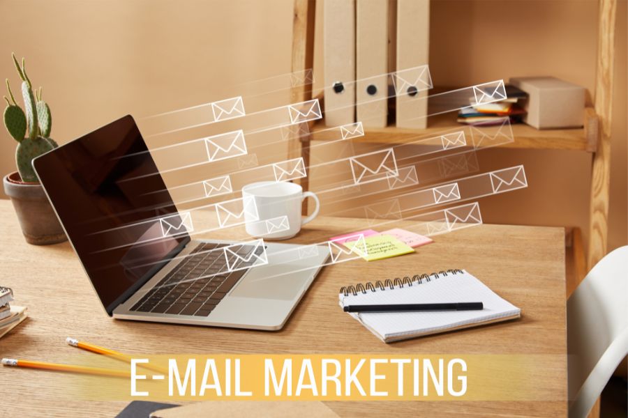 a laptop on a desk with mail and a word Email marketing