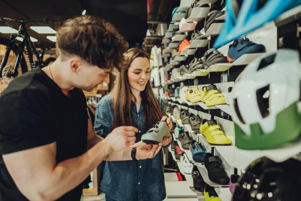 woman buying a cycling shoes in bike shop - running shoes  stockfoto's en -beelden