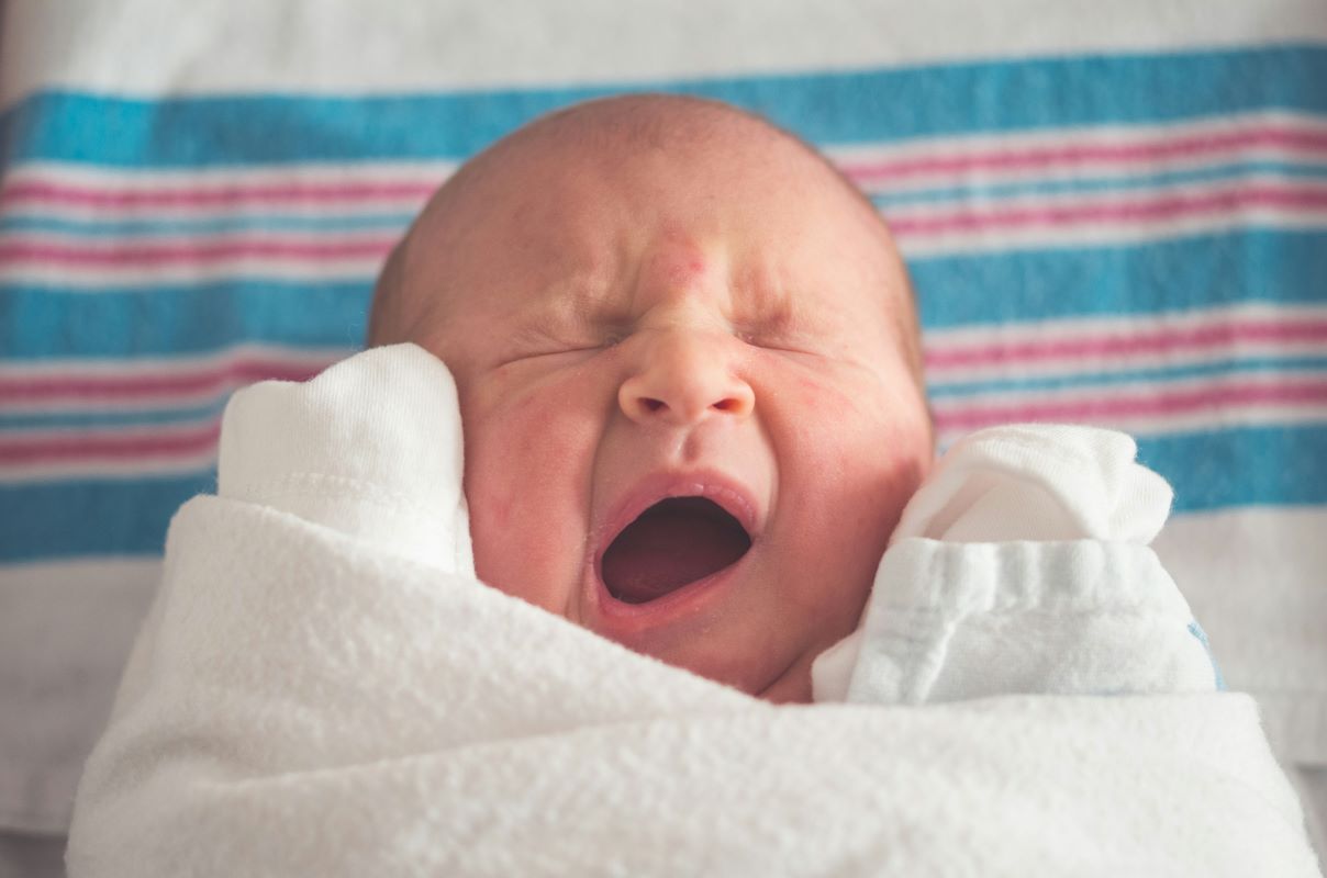 a newborn baby face with rashes on the cheeks and forehead