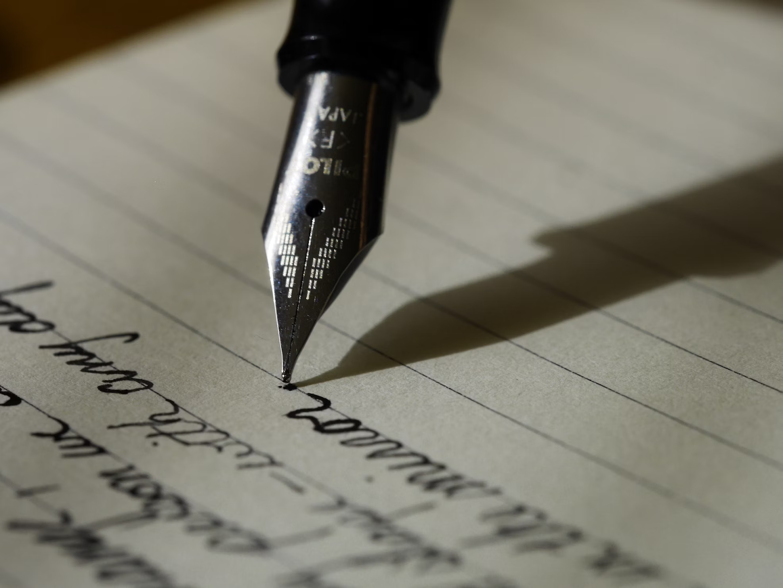 Ponta de uma caneta escrevendo em um pedaço de papel.