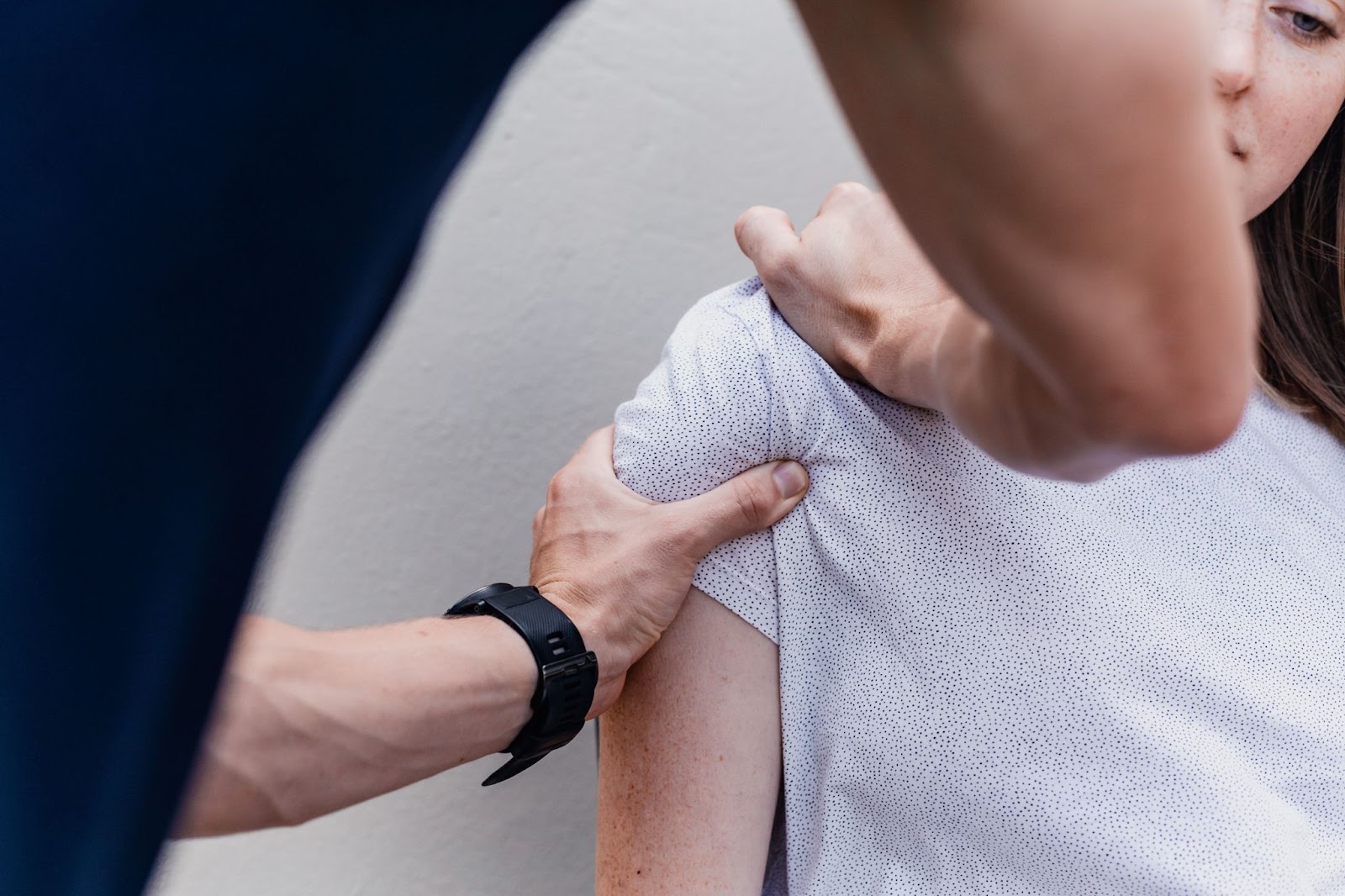 a woman having her shoulder palpated by a sports medicine professional at a kelowna multidisciplinary health clinic