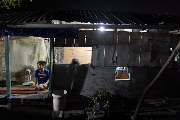 Do Hoang Trung briefly wakes up to the sounds of his grandmother preparing for a day's work on their houseboat in Can Tho, Vietnam, on Wednesday, Jan. 17, 2024. Trung and his twin sister stay with their grandmother, who sells steamed buns on a floating market to support her grandchildren since their mother left for better financial opportunities in Ho Chi Minh City. (AP Photo/Jae C. Hong)