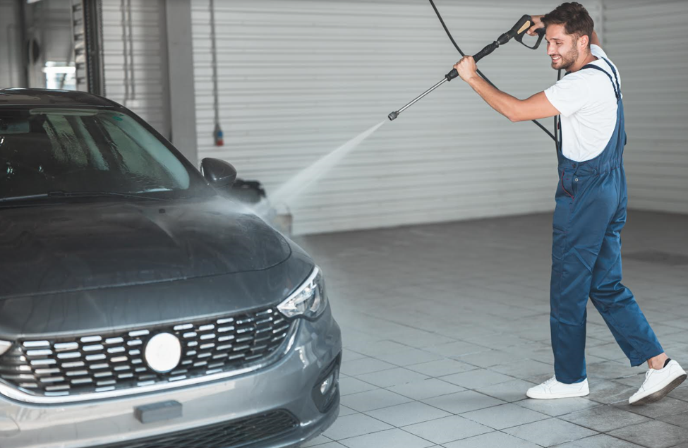 Man Using Water Sprayer To Wash His Car