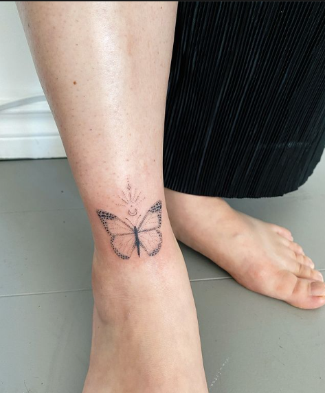 Butterfly tattoo on ankle in black ink