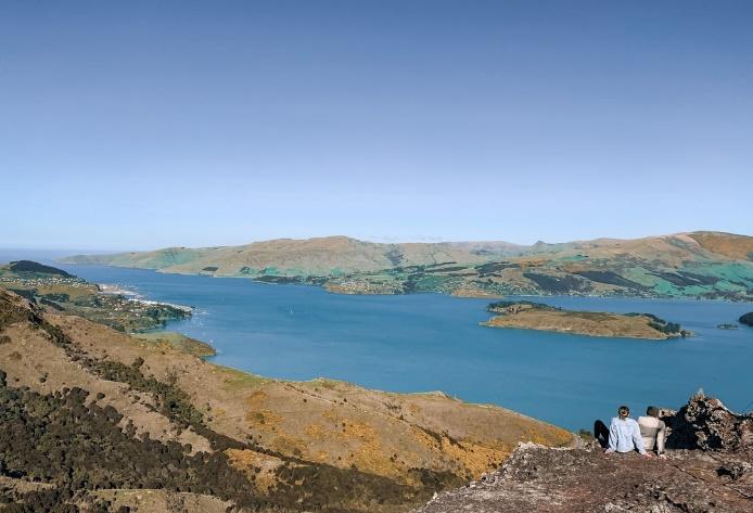 people sitting on rock formation near body of water during daytime