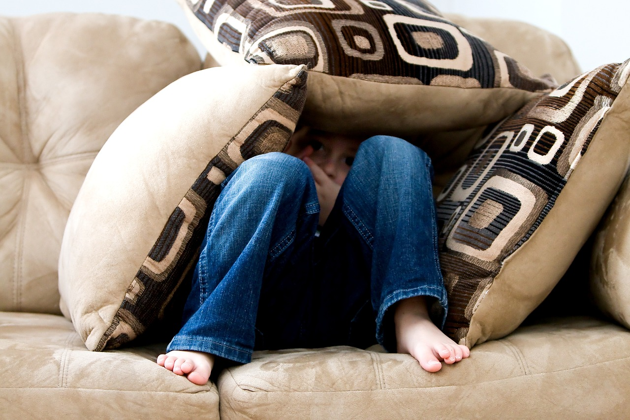 child hides under cushions