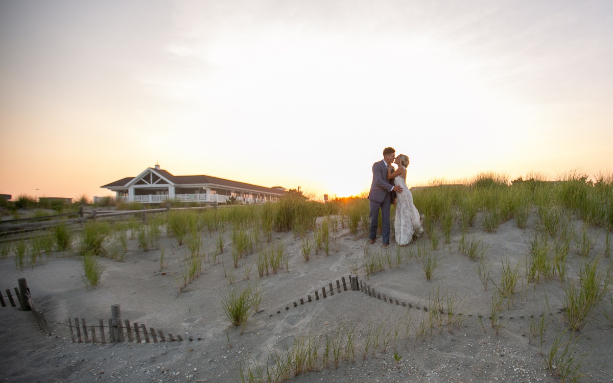 Couple embracing on the beach outside the ICONA beach wedding venue in Avalon, NJ