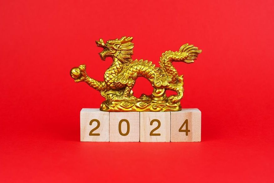 gold dragon statue atop wood blocks that spell out 2024 for lunar new year in february