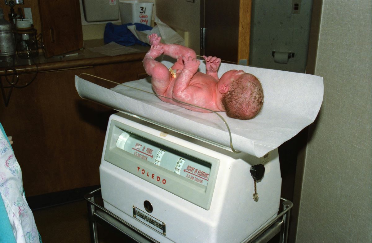 a nurse weighing a newborn baby