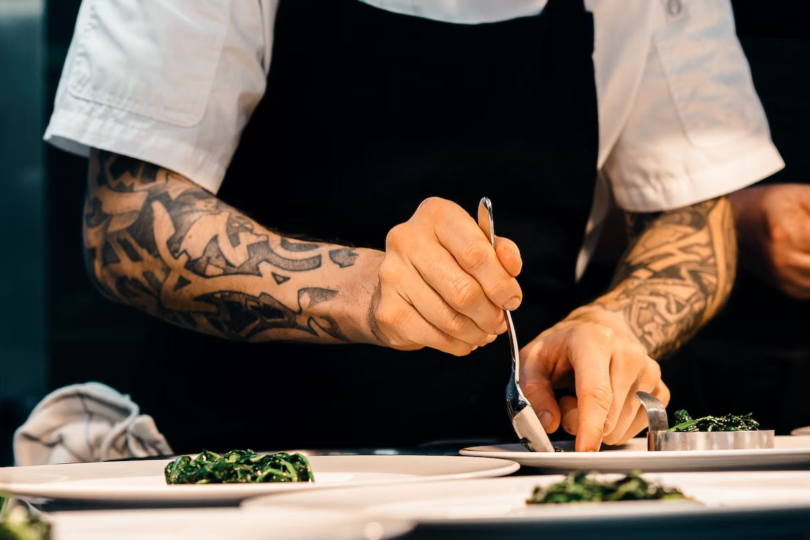 a chef adding sauce to a plate of food