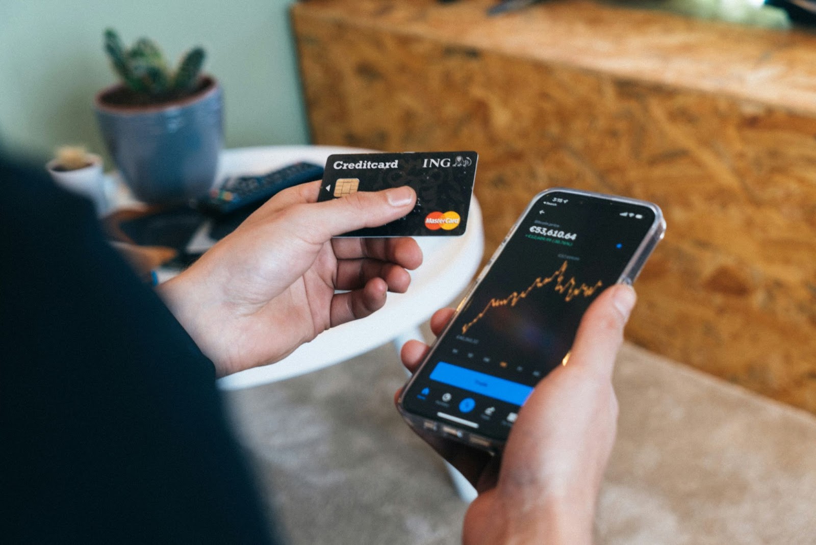 A person holding a smartphone in one hand and the other holding a crypto credit card