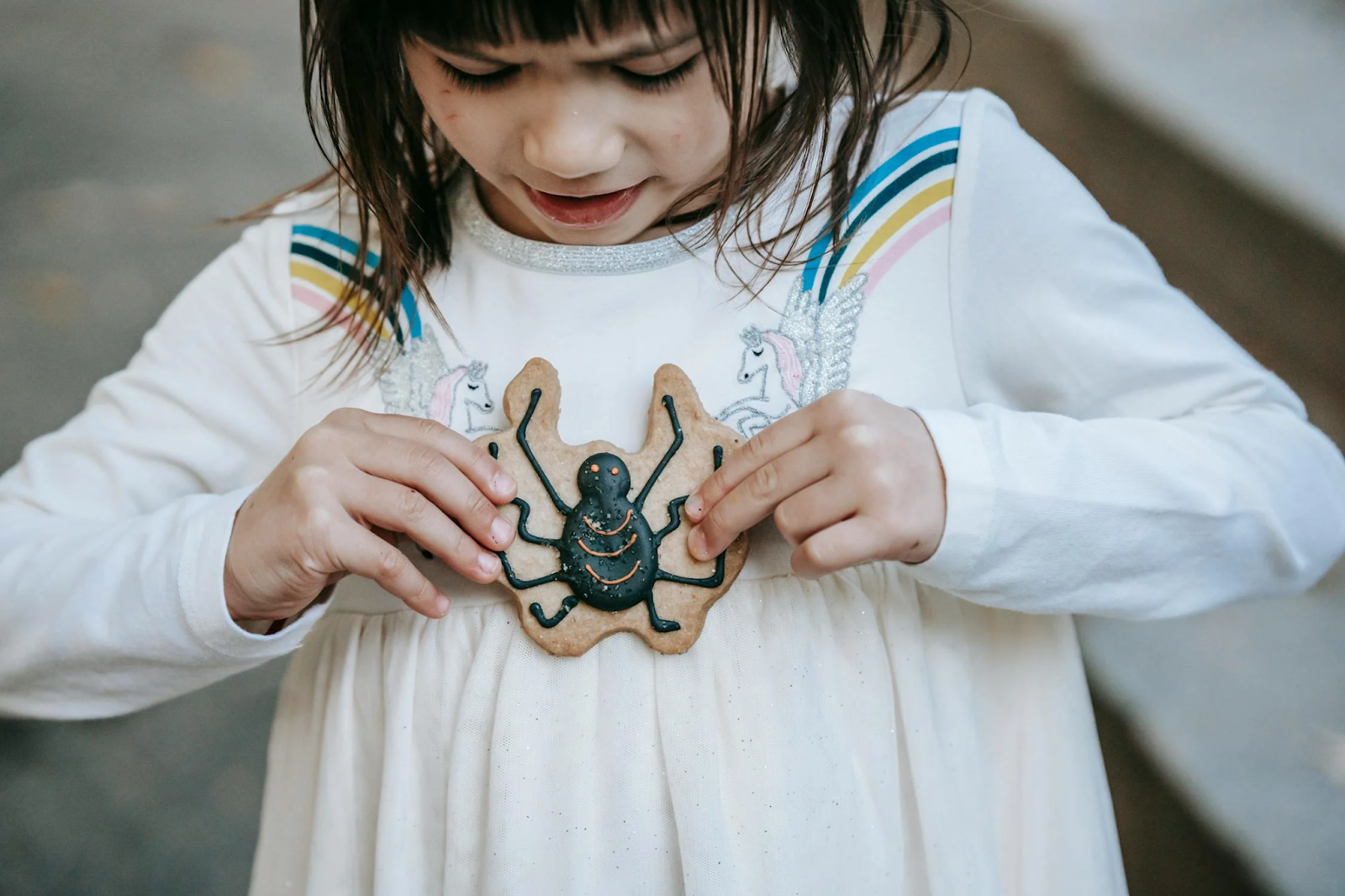 little girl holds a spider cookie