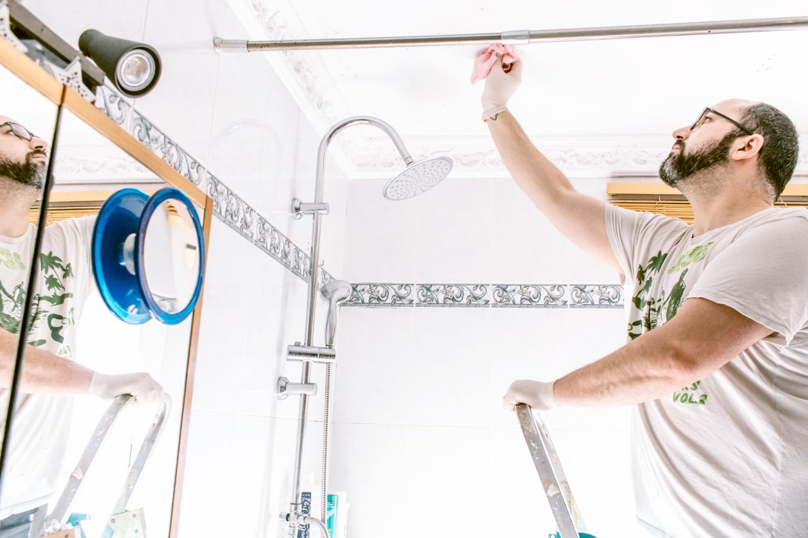 A man is cleaning mold stains from the bathroom.