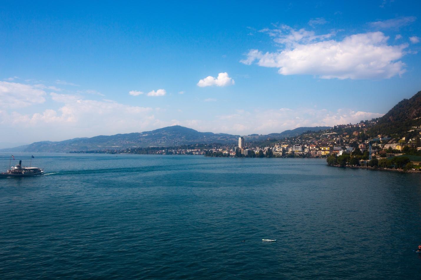 A body of water with buildings and mountains in the background

Description automatically generated