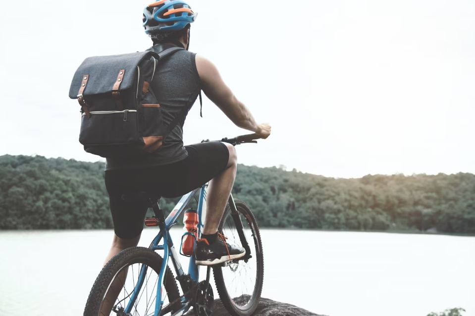 Ciclista com bagagem nas costas a beira de um lago.