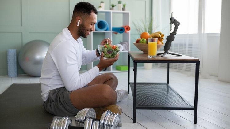 A person sitting on the floor eating a bowl of salad

Description automatically generated