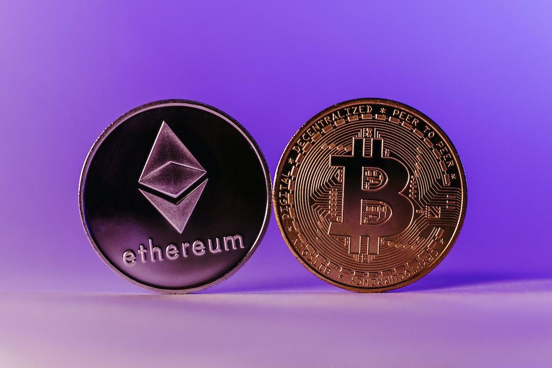 Free Bitcoin and Ethereum Coins Standing against a Purple Background Stock Photo