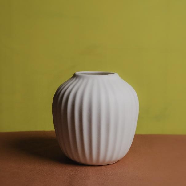 A white vase on a brown surface

Description automatically generated