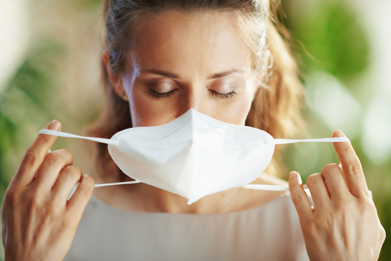 Mulher colocando máscara respiratória antes de iniciar o serviço de limpeza profissional.