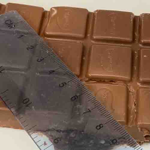 A clear plastic ruler on top of chocolate block with melted squares