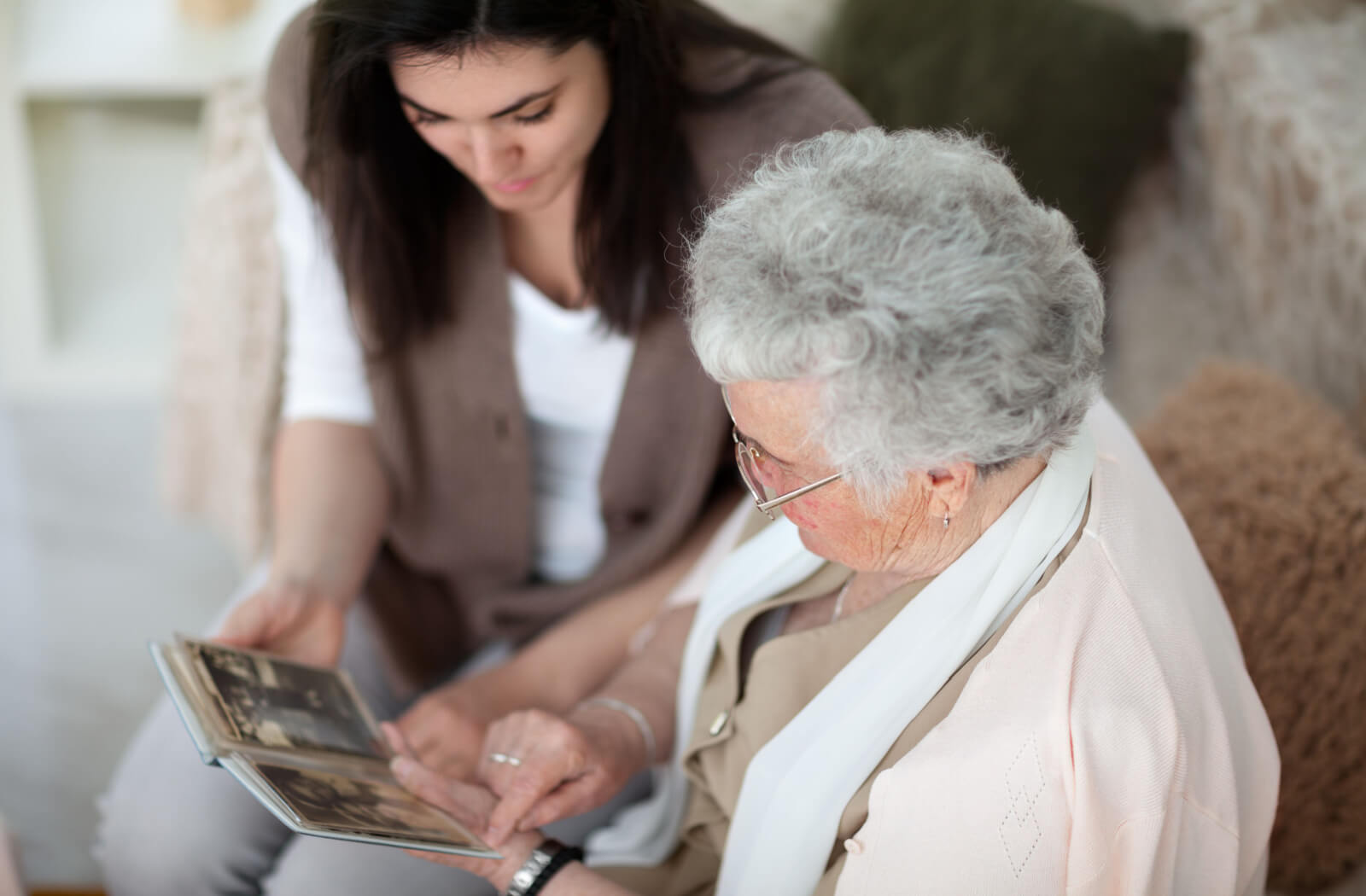A young woman looking through a photo album with her senior.