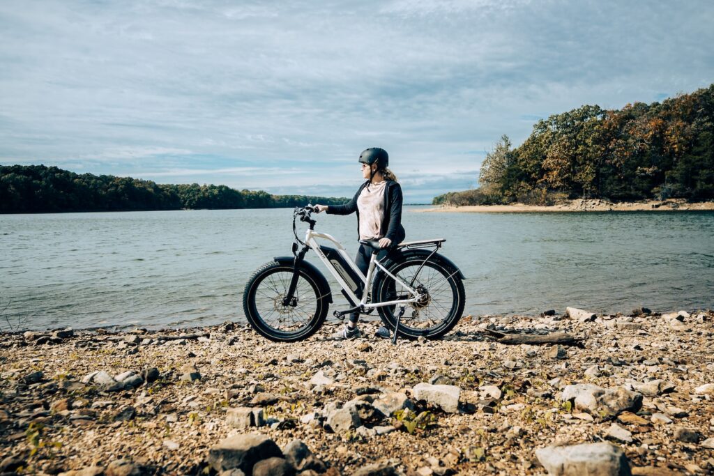 a woman standing next to a bike on a rocky shore