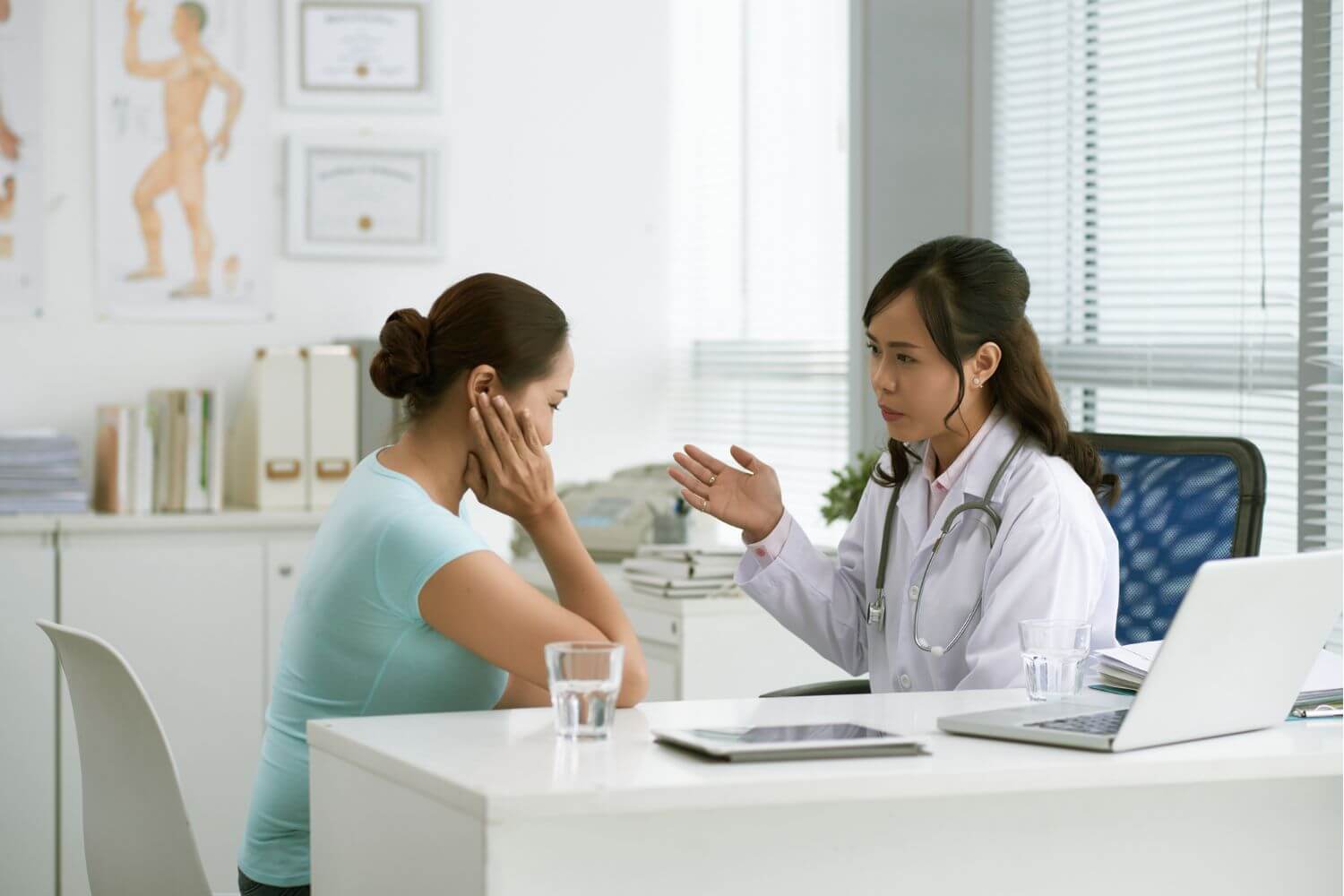 Woman sitting at a physicians desk while talking to her