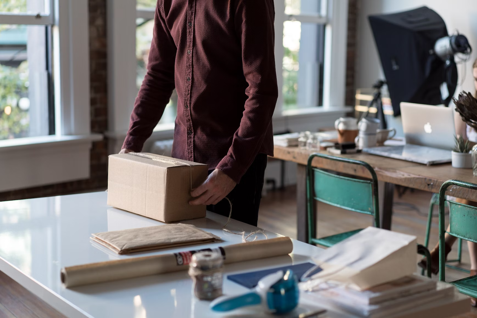 a worker in a dark burgundy button up in a studio about to open a small package